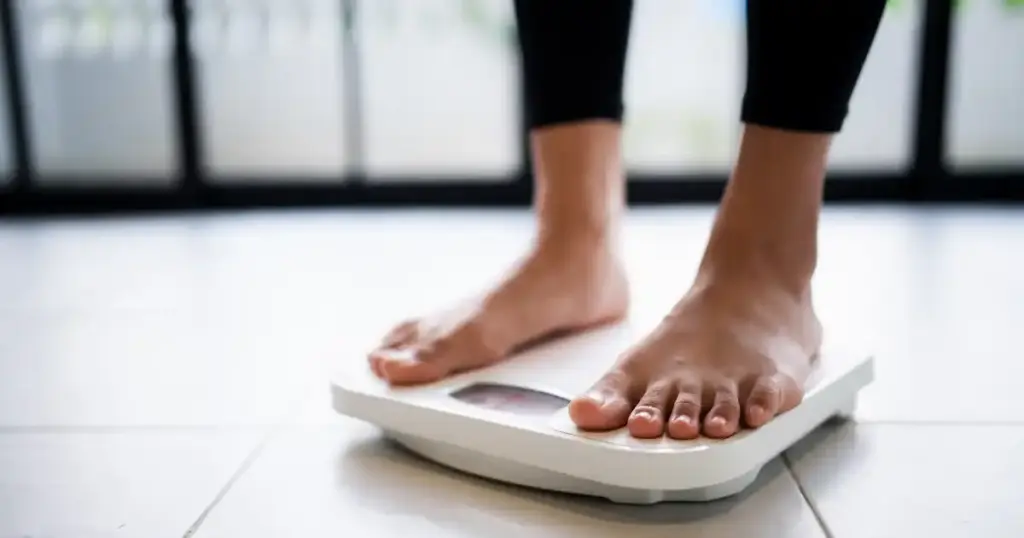 ダイエット中の女性が体重計に乗ってる
