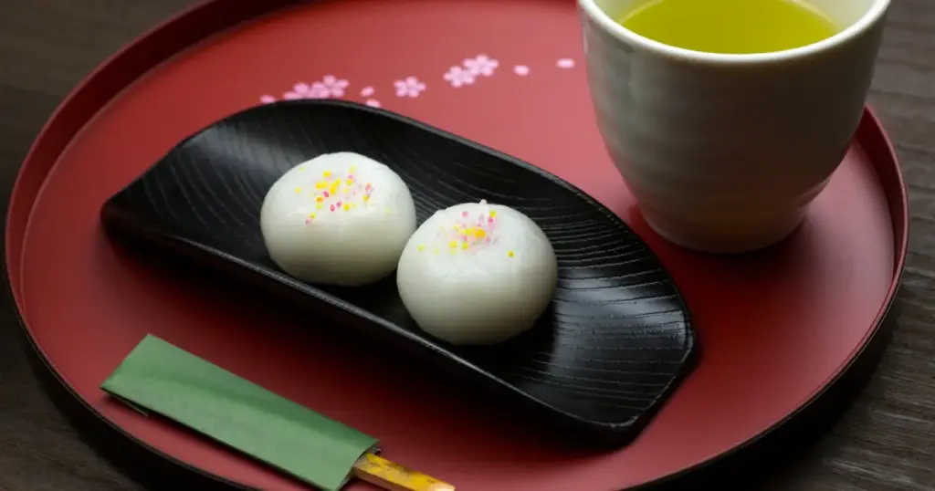 和風なお盆の上に、黒皿にのった大福とお茶がのっている。